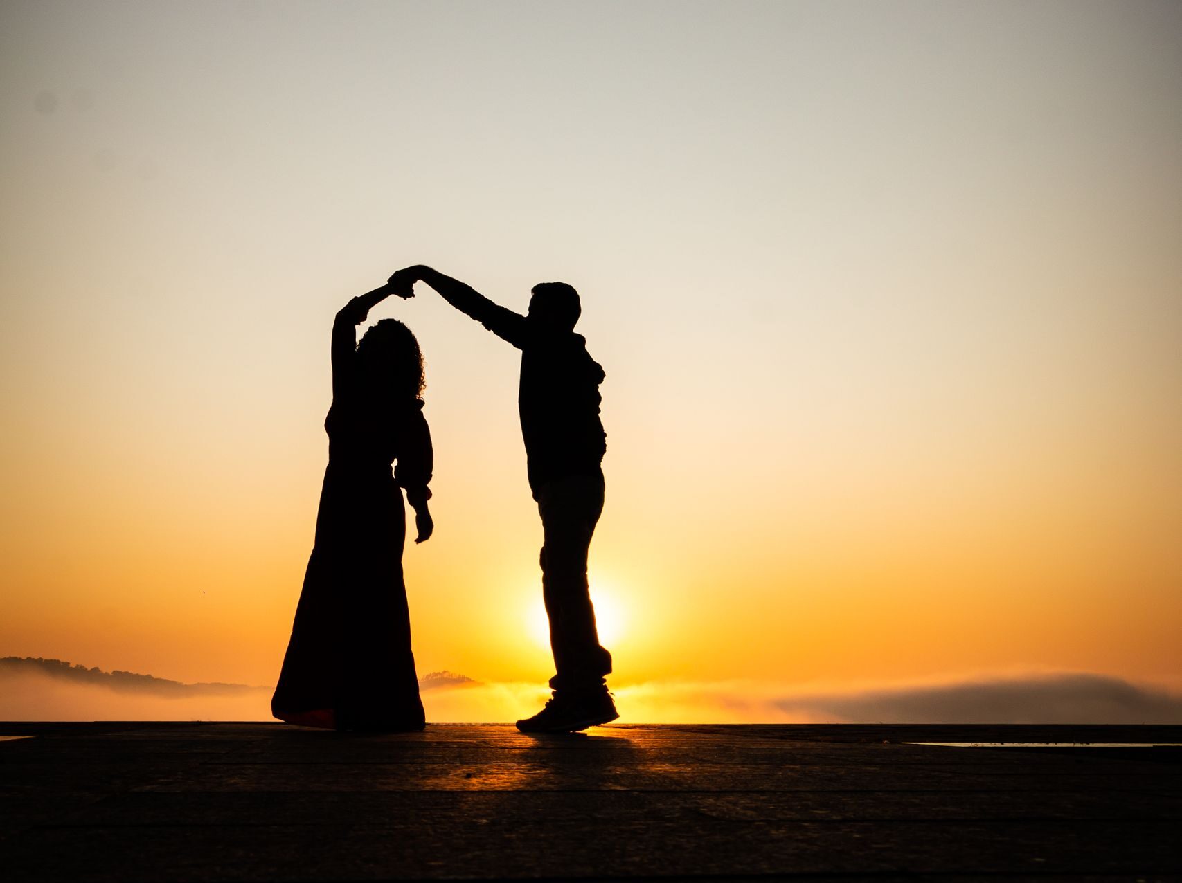 Silhouette of a couple dancing against a vibrant sunset, capturing love and romance.